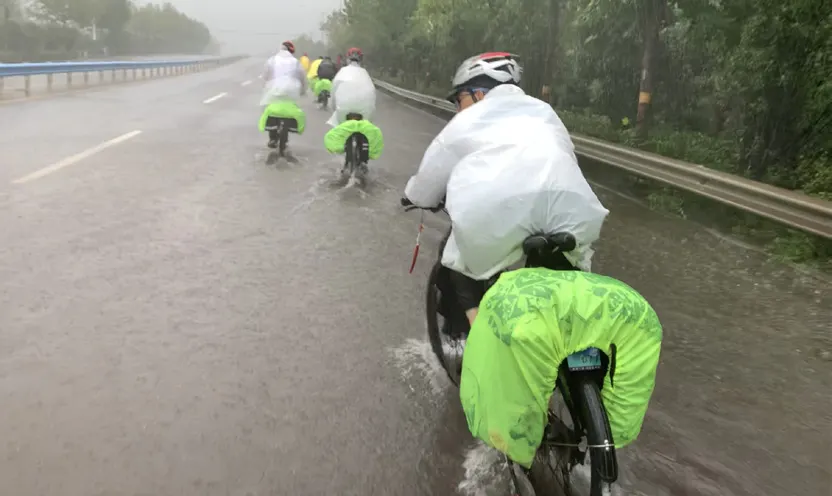 穿着雨衣的队员在积水的公路上骑行