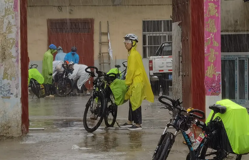 队员穿着雨衣在门前整理自行车
