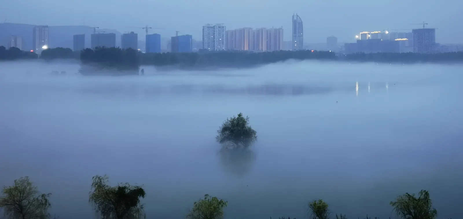 晨雾笼罩的丹江口江面与对岸楼群