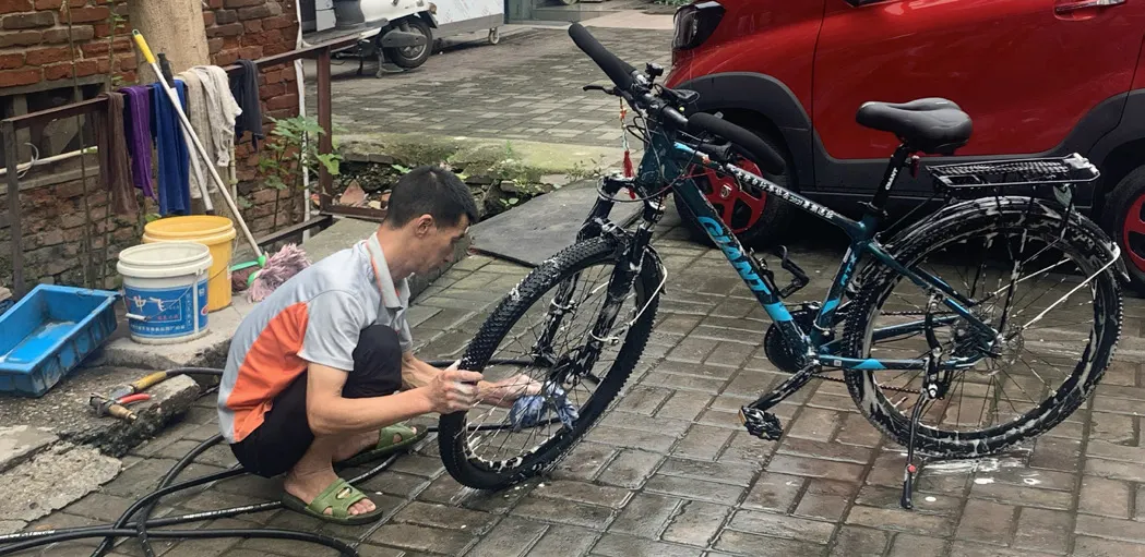 队员蹲在路边冲洗自行车
