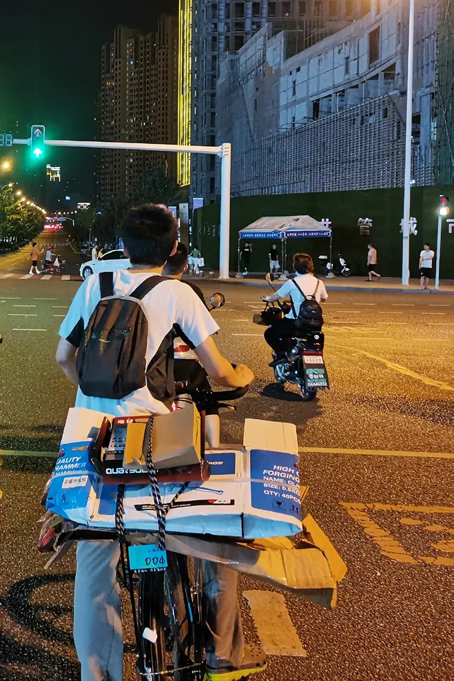 夜里,队员推着绑满纸箱的自行车过马路
