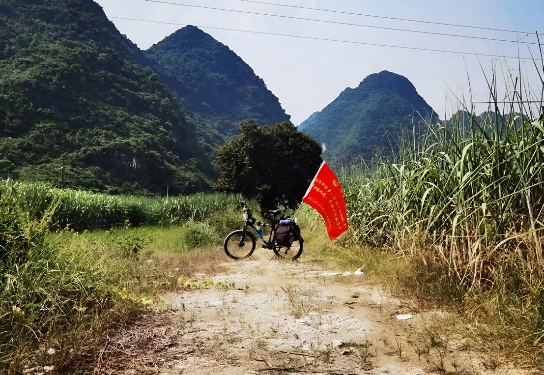 烂路边的土包上停着一辆插着红旗的自行车