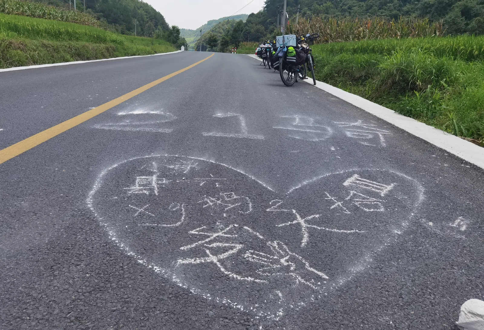 路面上粉笔写着“21 骑”,画着一颗心和队员们的名字