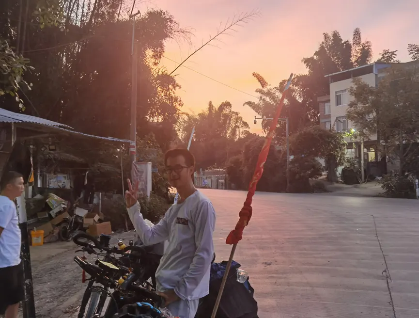 暮色中,一名队员在街边推着自行车比出剪刀手