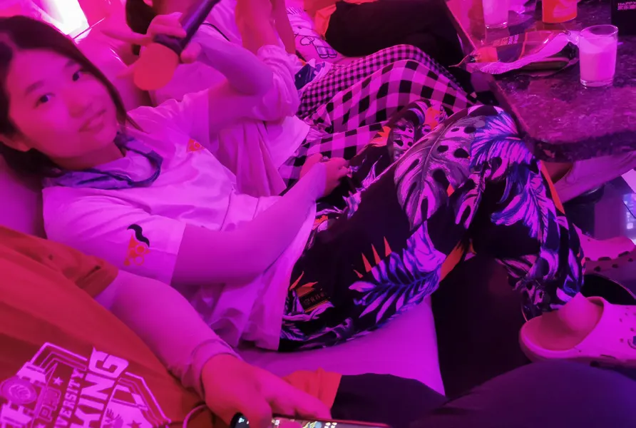 紫红灯光下,队员穿着花裤子靠坐在沙发上