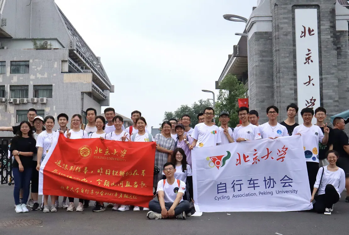 两团队员在北大东门前举着红旗与会旗合影