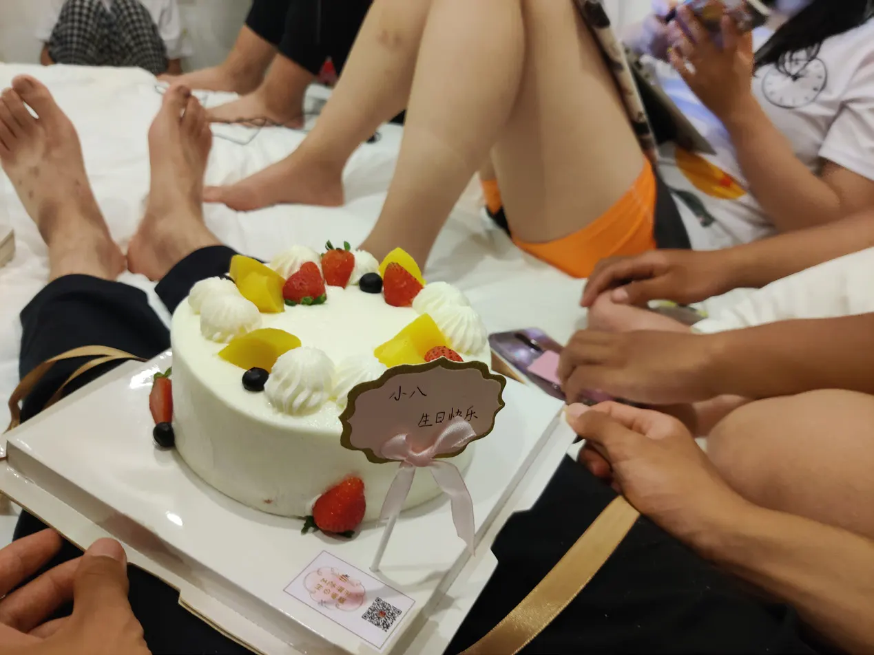 众人围坐在床上,中间是一个插着“小八生日快乐”牌子的蛋糕