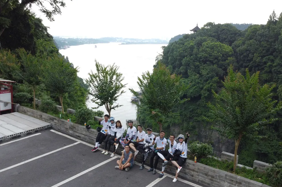 队员们坐在江边山崖上的停车场边