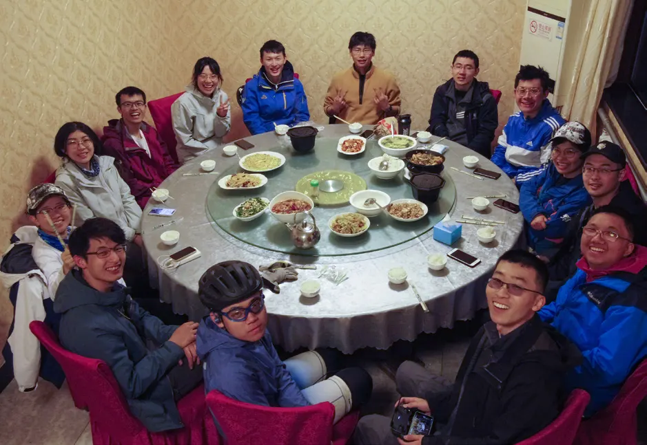 众人围坐在圆桌边吃饭,回头看向镜头