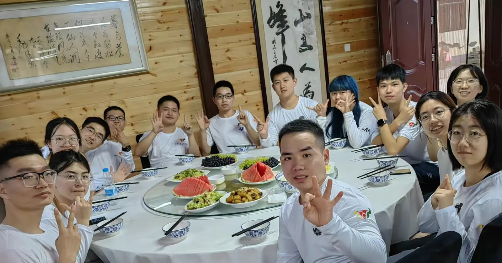 团员们围坐在饭桌旁举杯