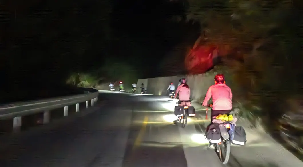 夜里亮着车灯骑行的团员