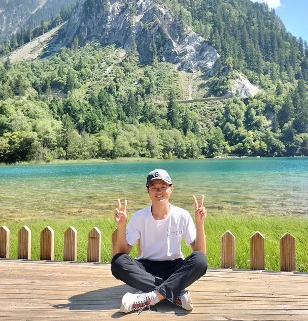 成绩盘腿坐在九寨沟的湖边
