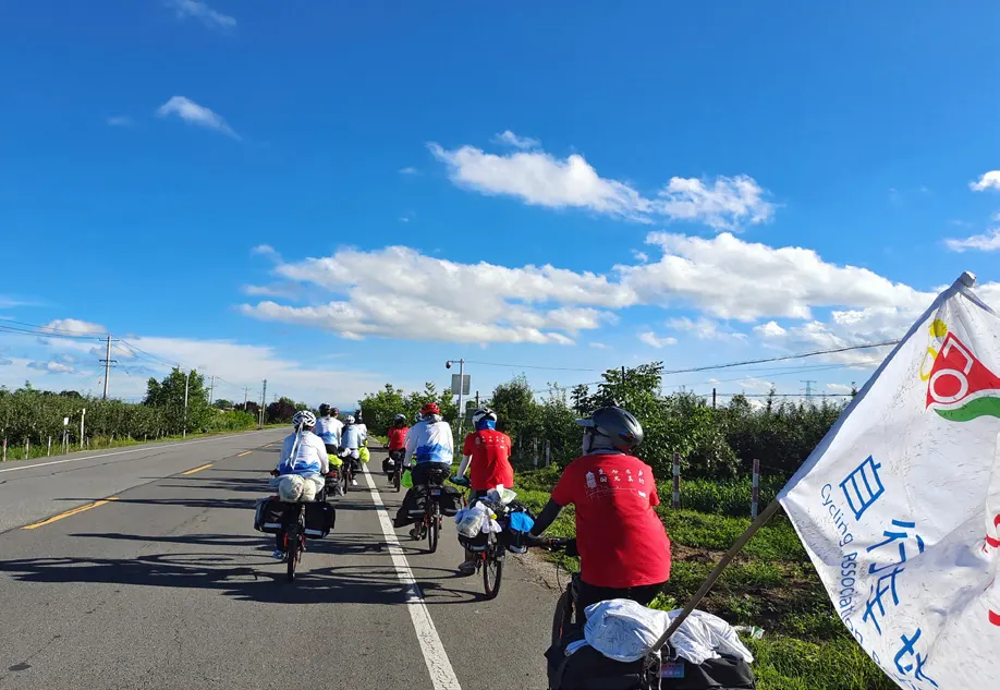 扛着车协旗的骑行团行进在公路上