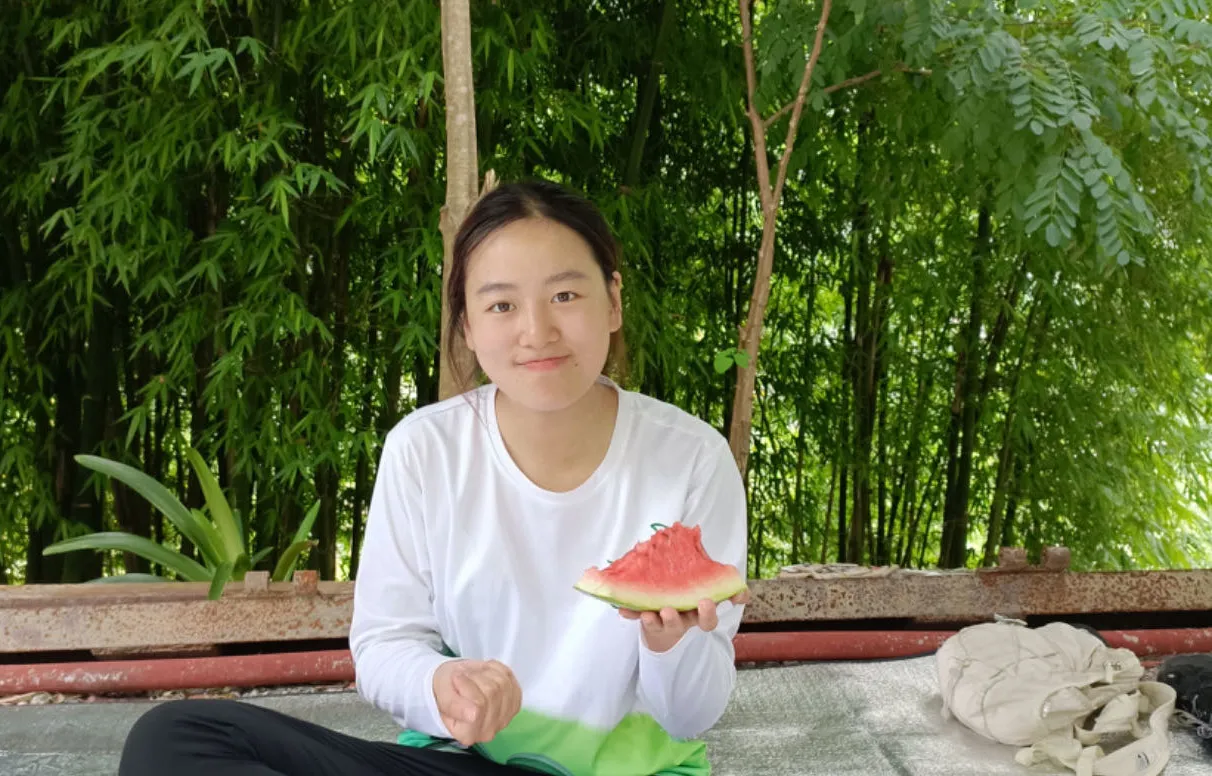 团员捧着一块西瓜坐在院子里